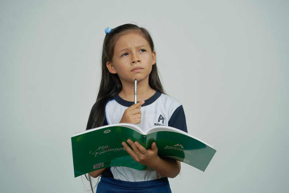 O studentă răsfoiește un caiet cu notițe, la un birou din cămin, lângă o cană de ceai