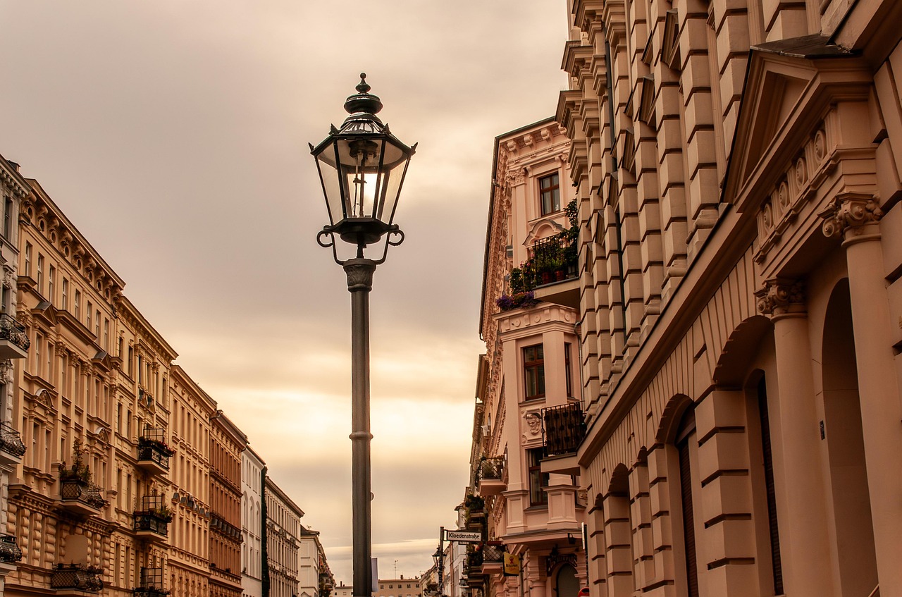 Stradă liniștită de oraș cu o tarabă cu flori și câțiva trecători la pas