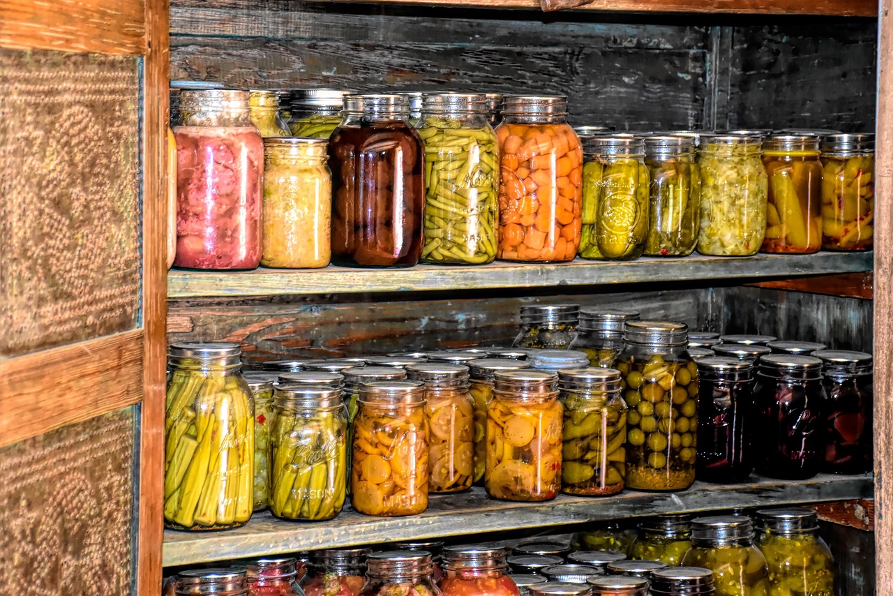 Rafturi de cămară cu borcane de cereale, leguminoase și conserve, aranjate pe categorii
