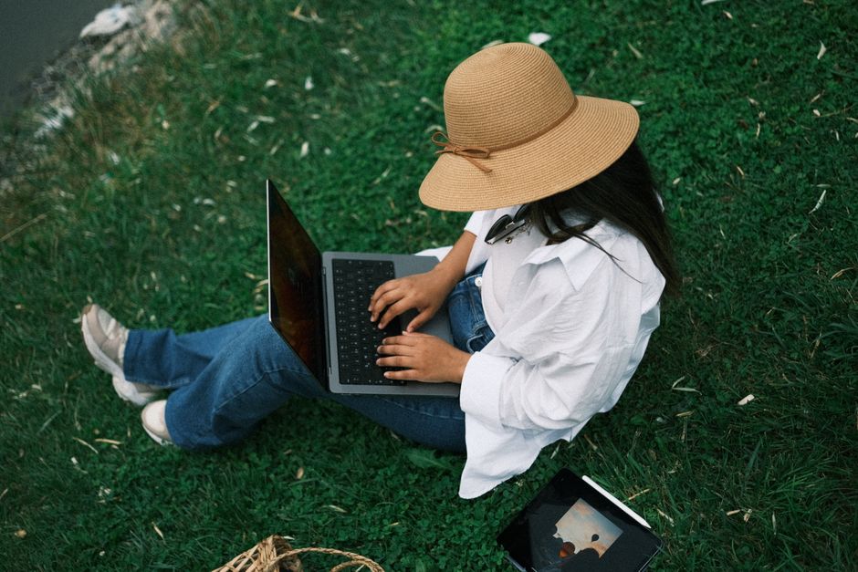 Doi studenți lucrează la laptop într-o cameră de cămin, cu o plantă pe birou