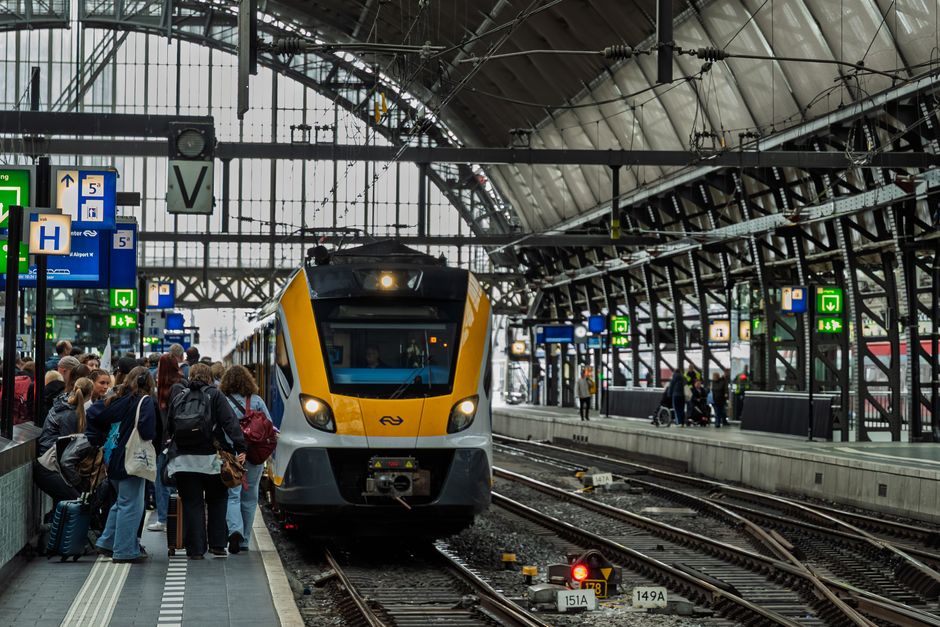 Navetist care citește pe telefon într-un tren aglomerat dimineața