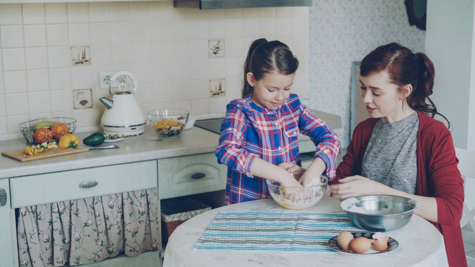 Cutii de carton pe podeaua unei bucătării, cu o familie care despachetează seara