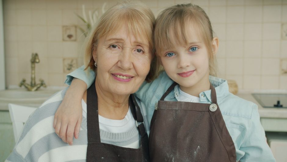 O familie pregătește micul dejun în bucătărie, cu rucsacuri lângă ușă
