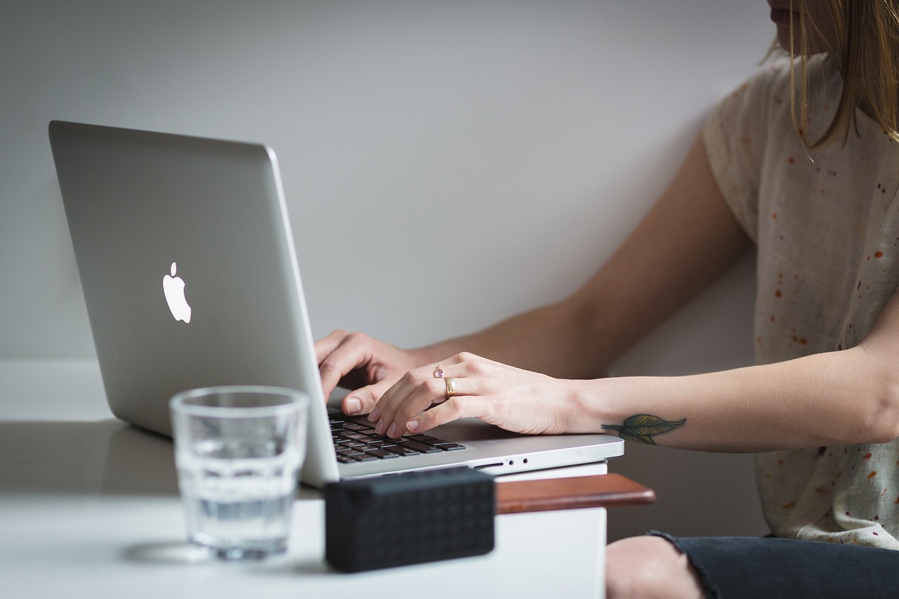 Un candidat și un recrutor își strâng mâna la o masă de birou, cu un laptop deschis între ei