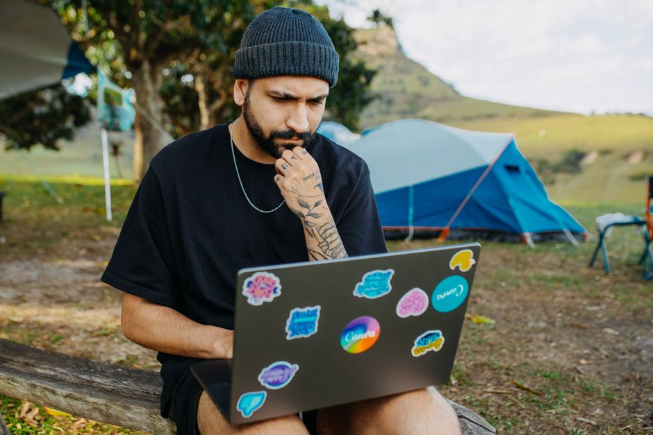 Femeie cu un caiet și un laptop la o masă de lucru lângă fereastră