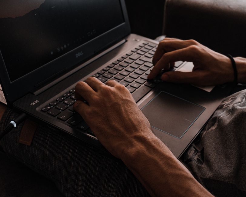 O femeie sortează acte și hârtii medicale la birou, cu laptopul deschis