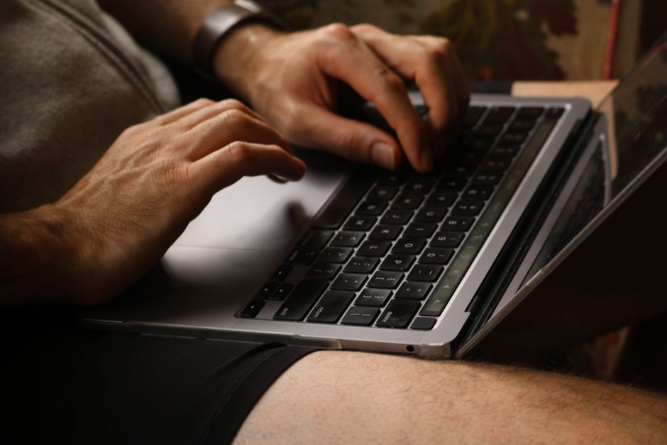 Femeie care gătește în bucătărie, cu laptopul deschis pe masă în fundal