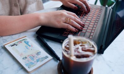 O femeie deschide un colet la masa din living, cu laptopul alături