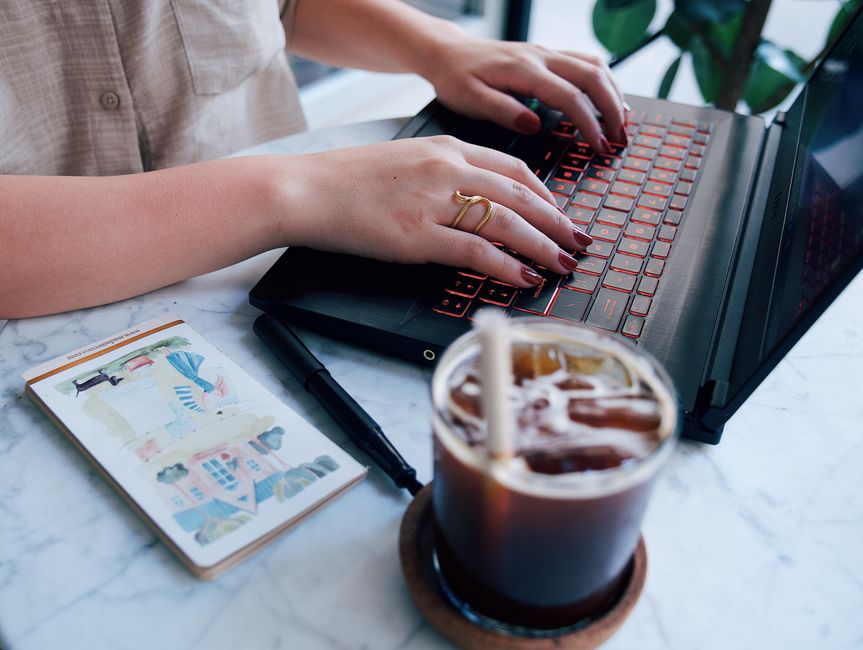 O femeie deschide un colet la masa din living, cu laptopul alături
