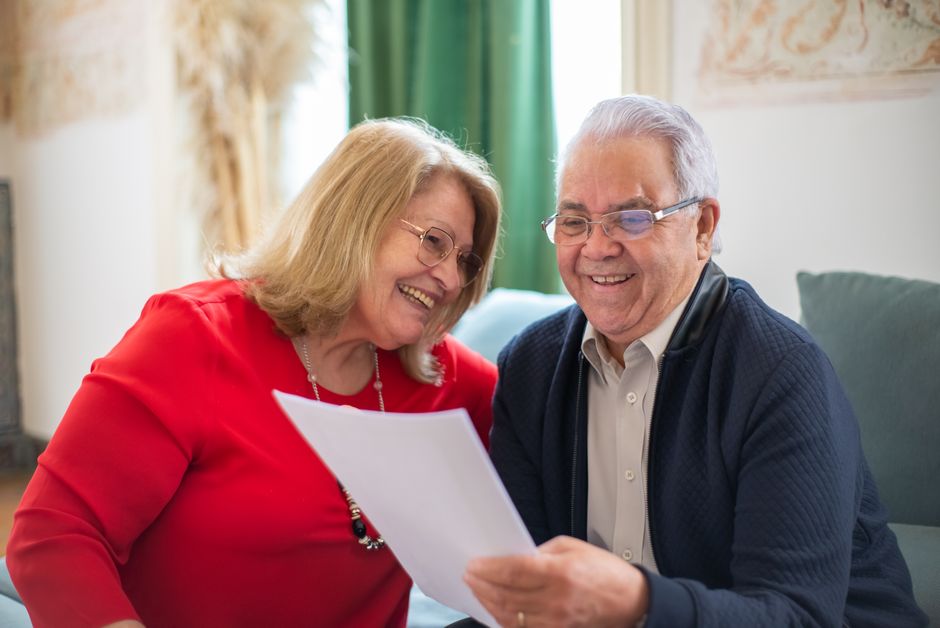 Pereche de seniori studiind o hartă lângă o mașină, pe o alee de munte