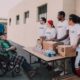 Femeie care ajută un bărbat în vârstă să se așeze pe canapea, într-o locuință liniștită