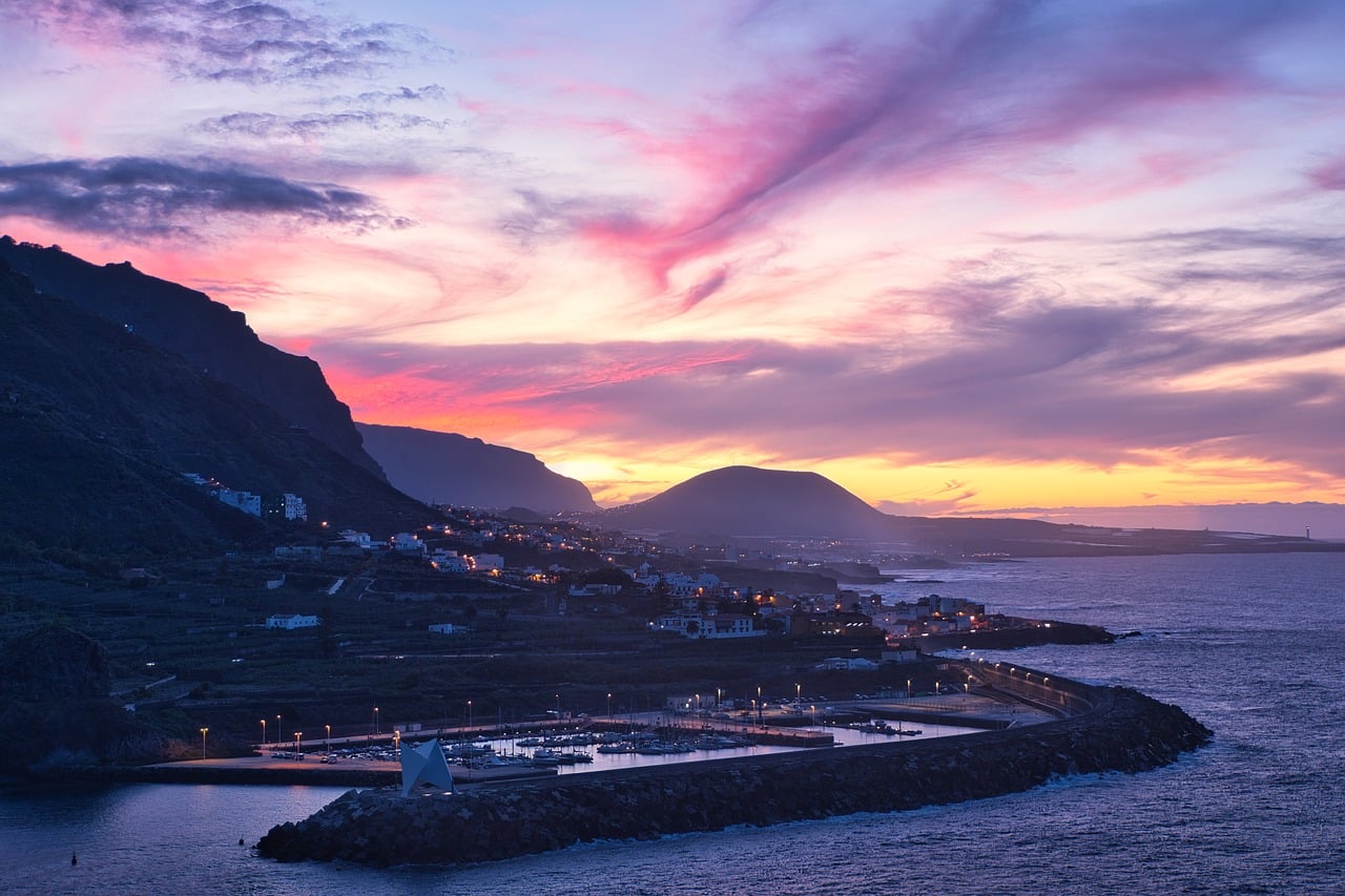 Coasta stâncoasă din Tenerife, cu valuri și vulcanul Teide în depărtare