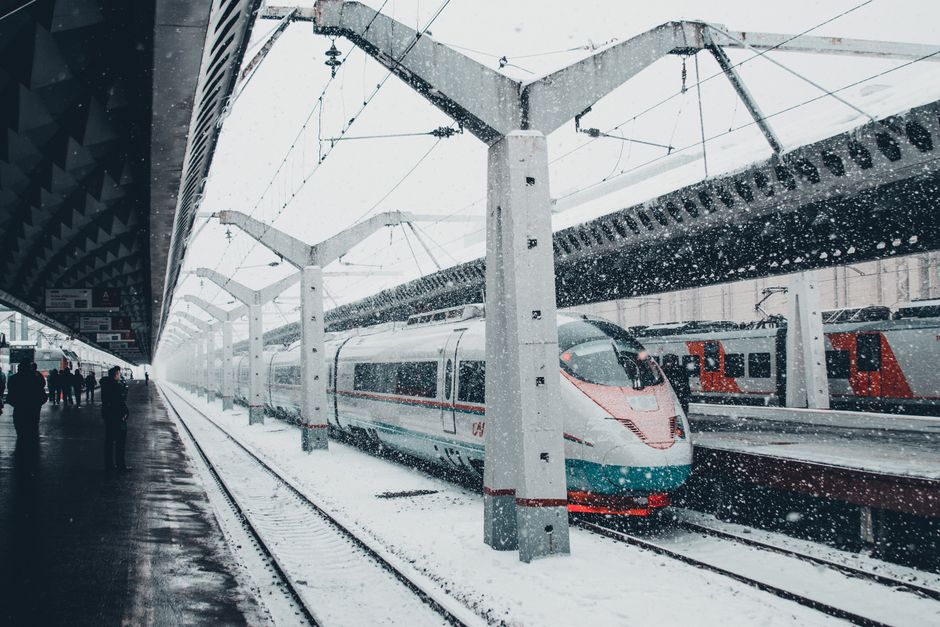 Navetist cu rucsac pe peronul unei gări, într-o dimineață cu ceață ușoară