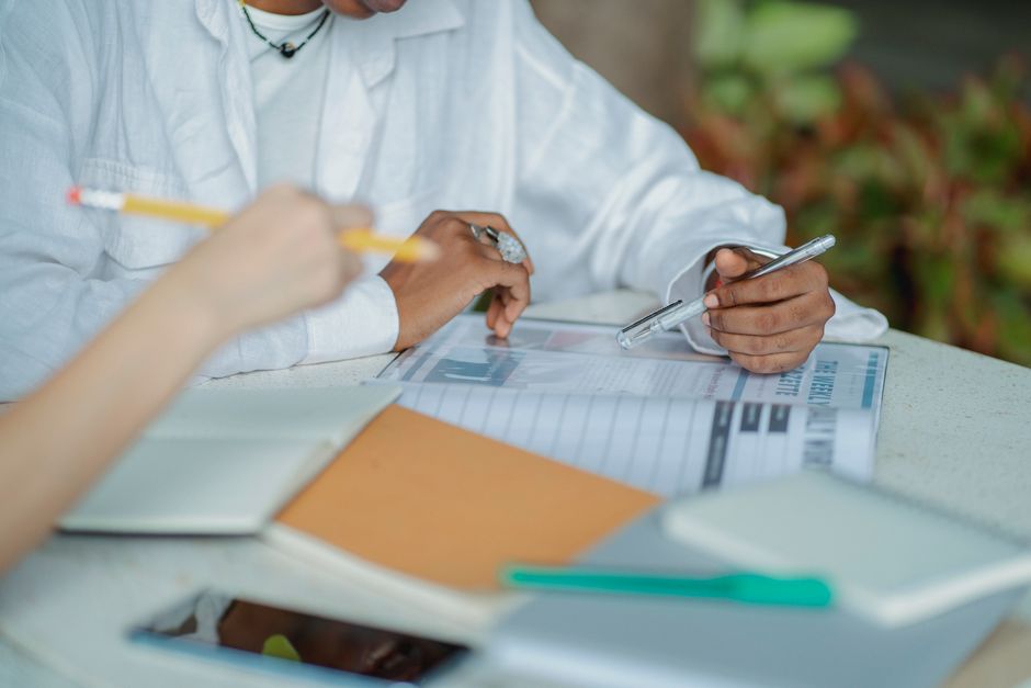Student la birou, cu cărți deschise și o mână la obraz, privind gânditor