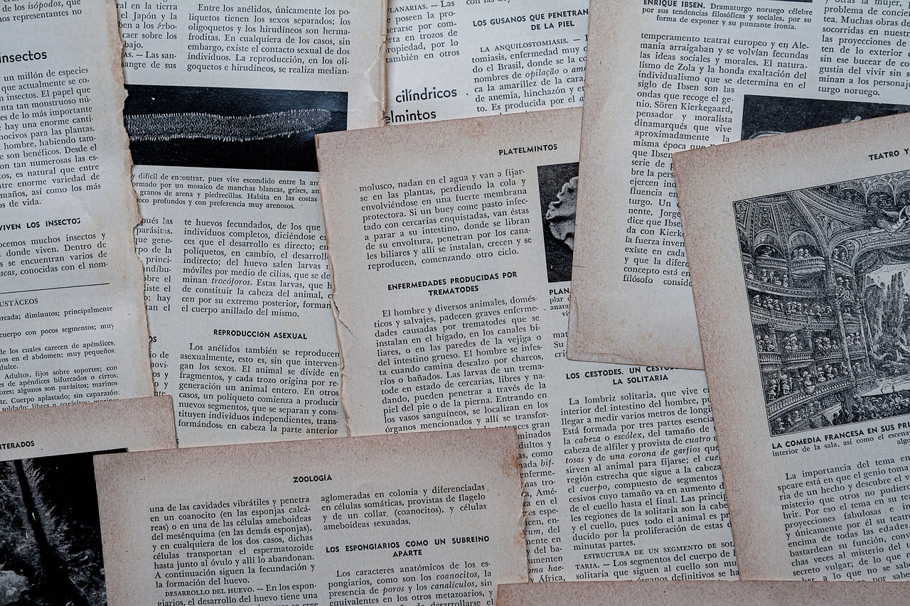 O tabletă mai veche așezată pe un raft, lângă o carte deschisă și o lampă de citit
