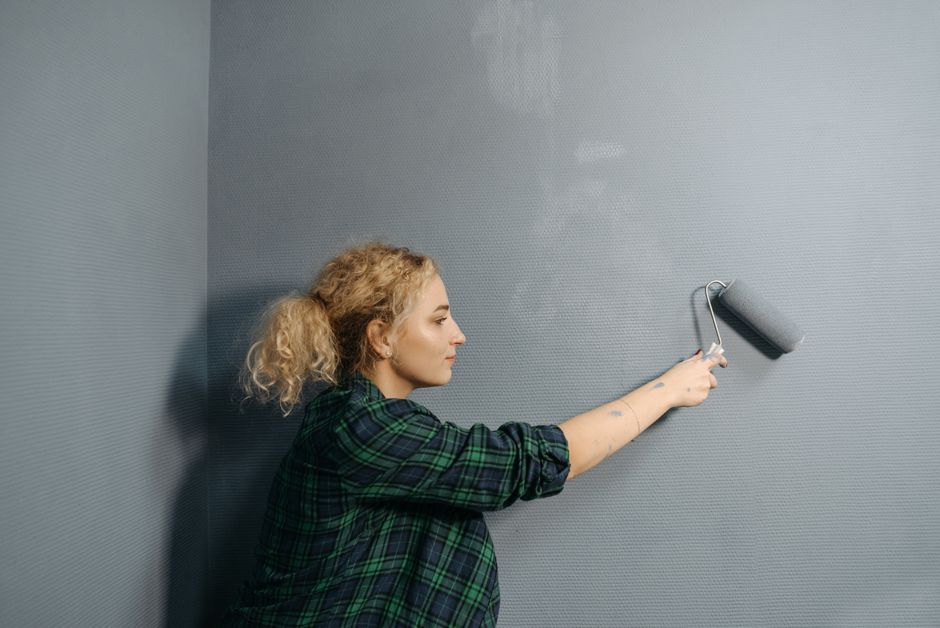 Un adult marchează cu creionul locul unui raft pe un perete alb, într-o cameră luminoasă
